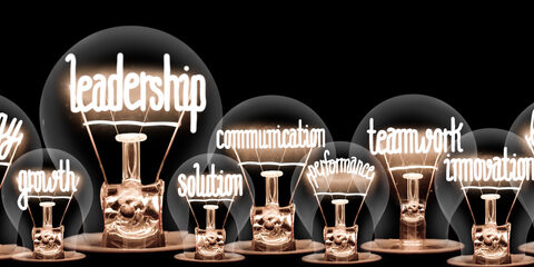 Group of light bulbs group with shining fibers in a shape of Leadership, Strategy, Teamwork and Solution concept related words isolated on black background