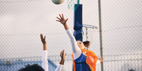 Netball, goal shooting and defense of a girl athlete group on an outdoor sports court. Aim, sport game and match challenge of a black person with a ball doing exercise and training in a competition.